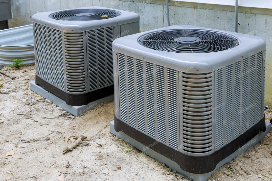 Two new central air conditioner condensers installed outside a home