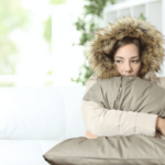 woman wearing winter coat inside because furnace is broken